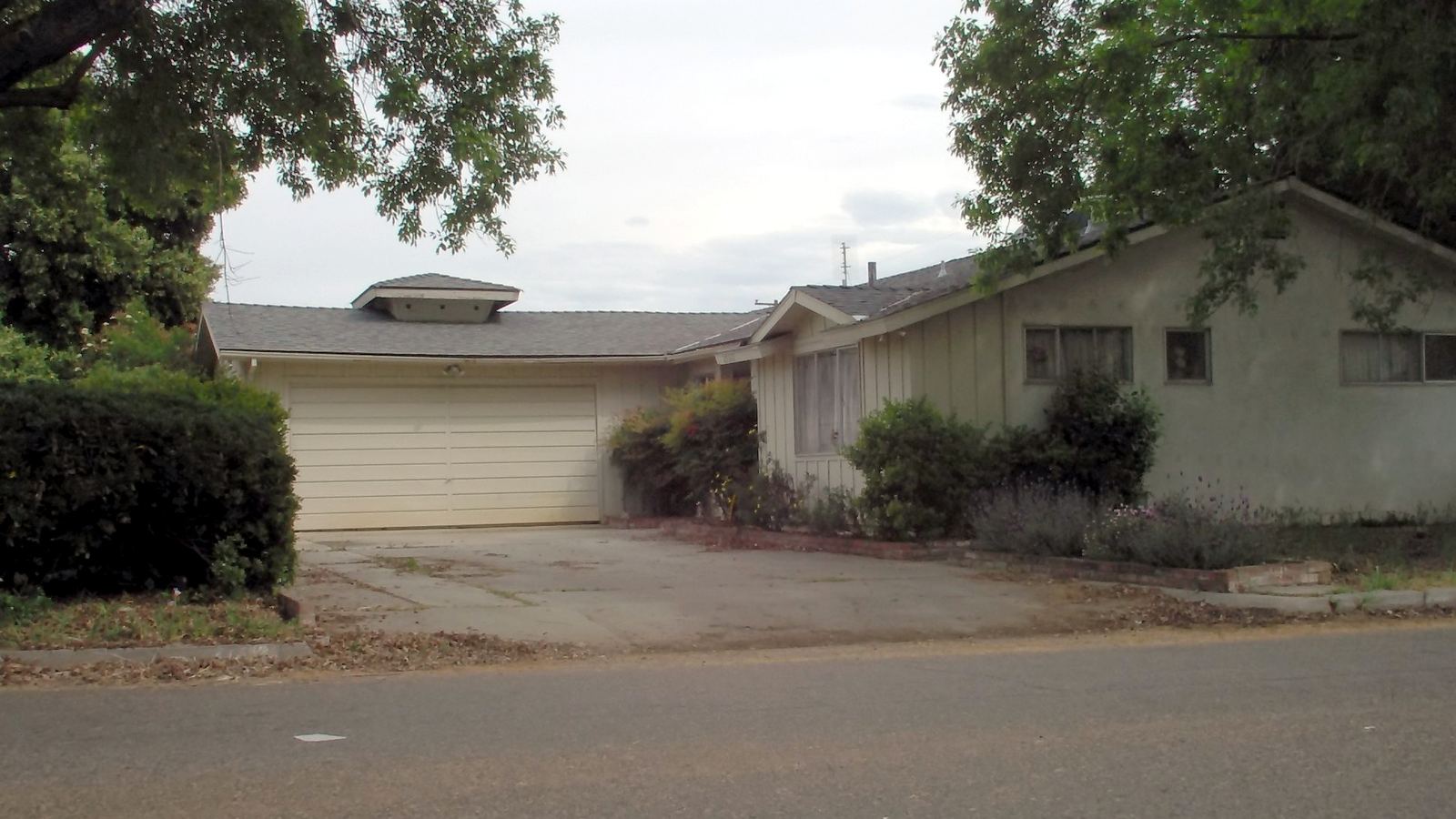 A 1950s ranch-style house with an attached garage on a quiet street
