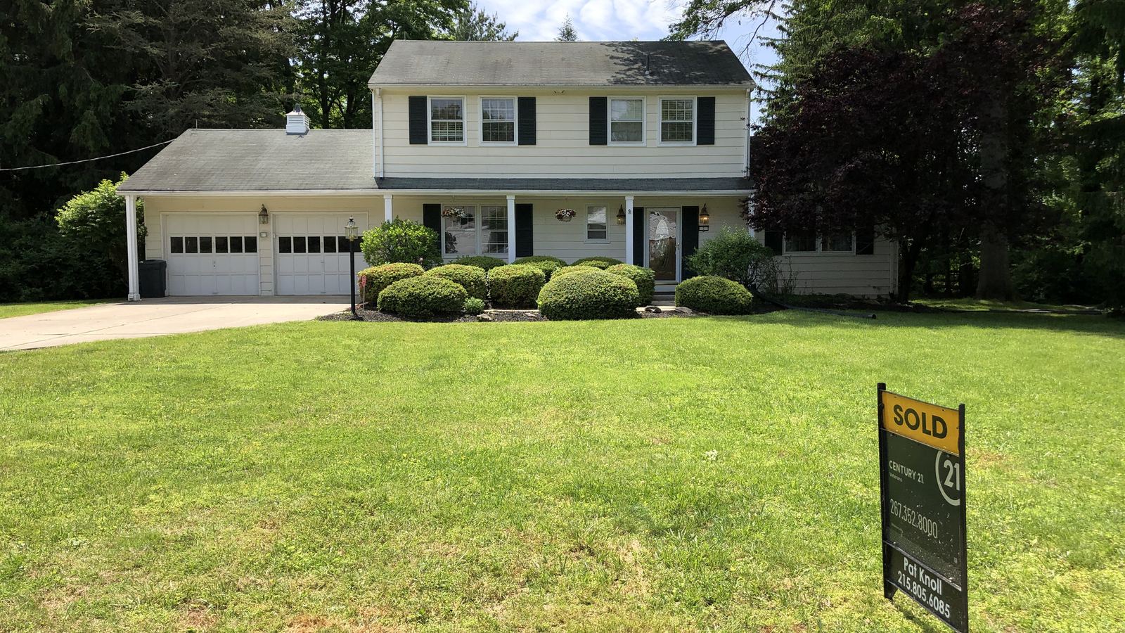 A 'Sold' sign on the lawn of a two-story colonial house