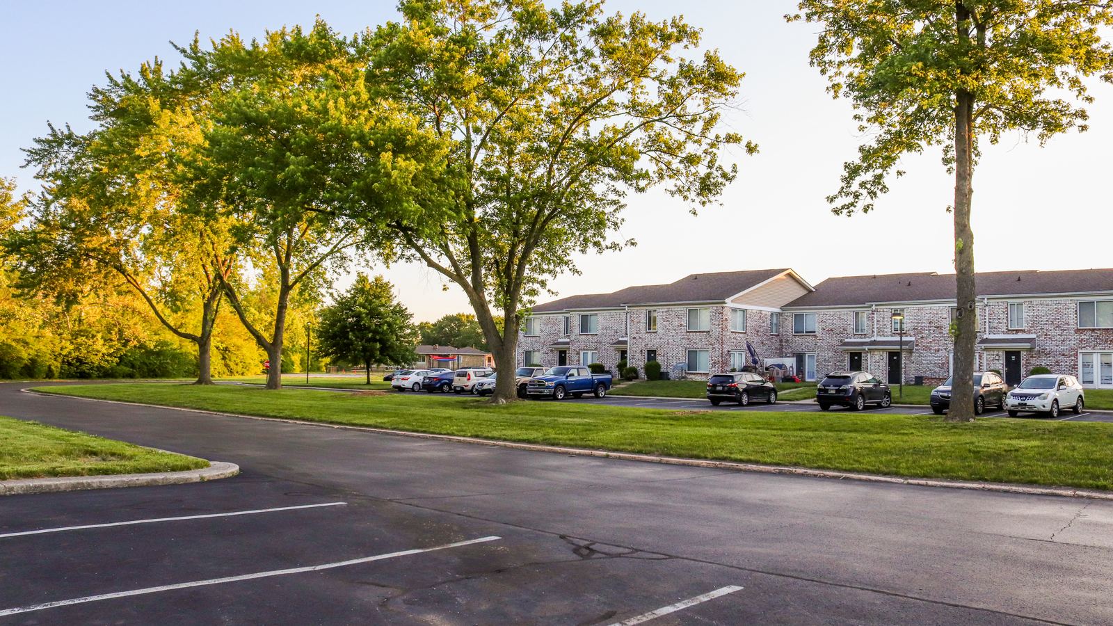 Two-story garden apartment buildings beside a parking lot