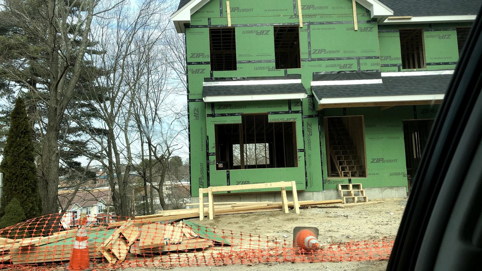 A new two-story house wrapped in green sheathing during construction
