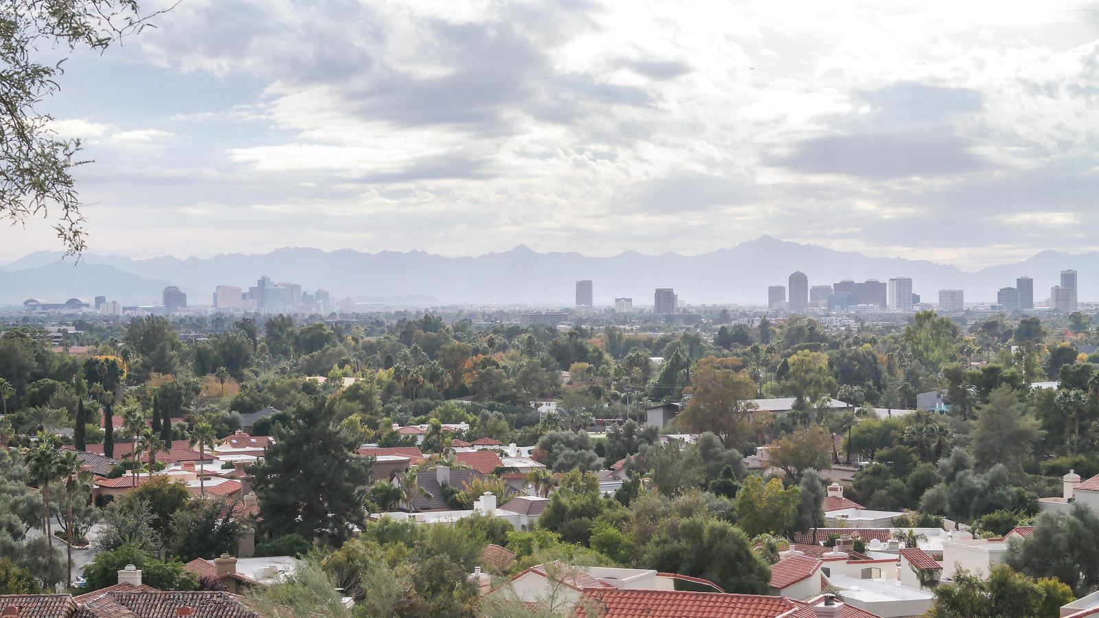 Tile-roofed homes in Phoenix with the downtown skyline and mountains in the distance