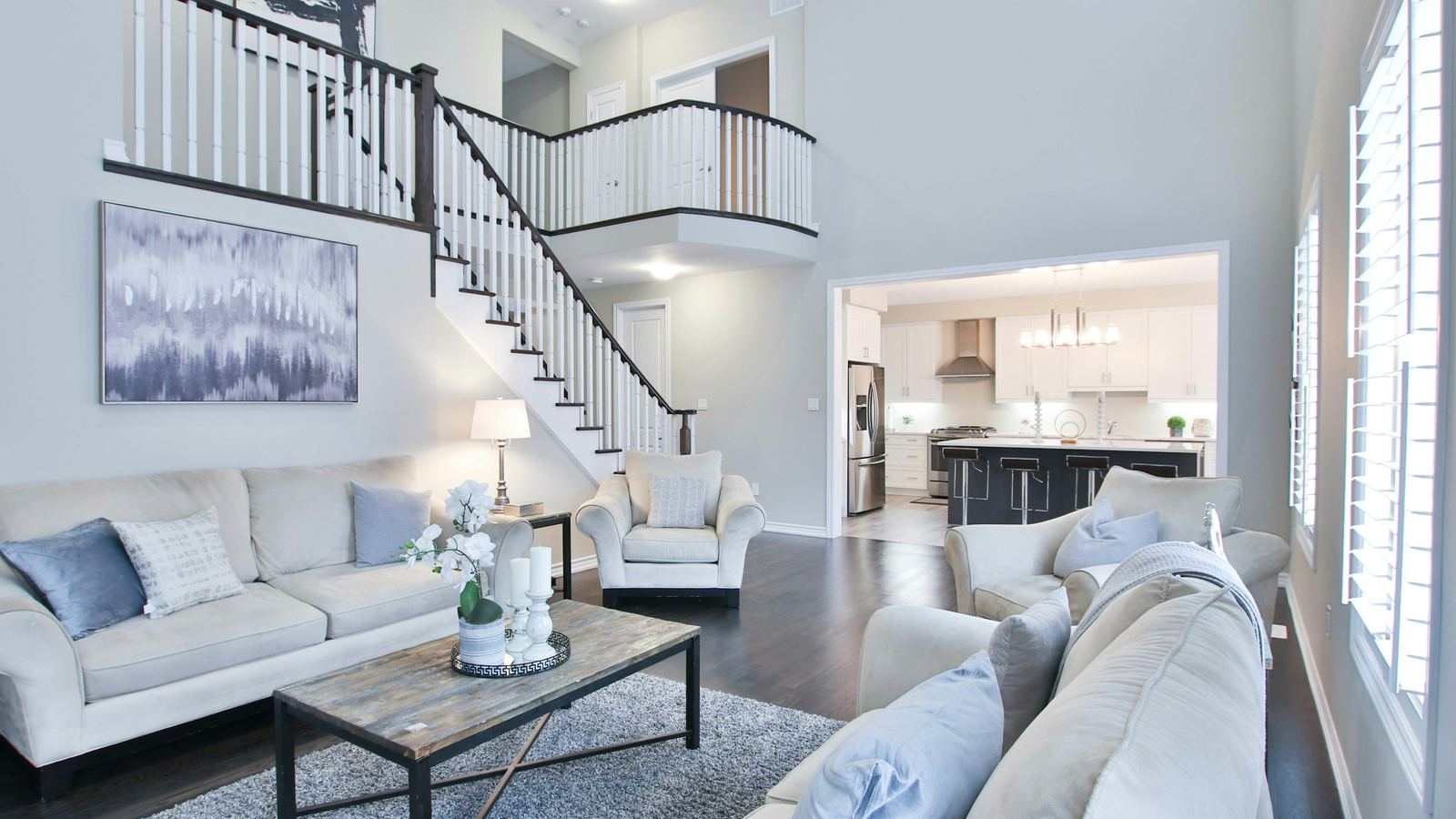 Bright staged living room with a staircase and an open kitchen