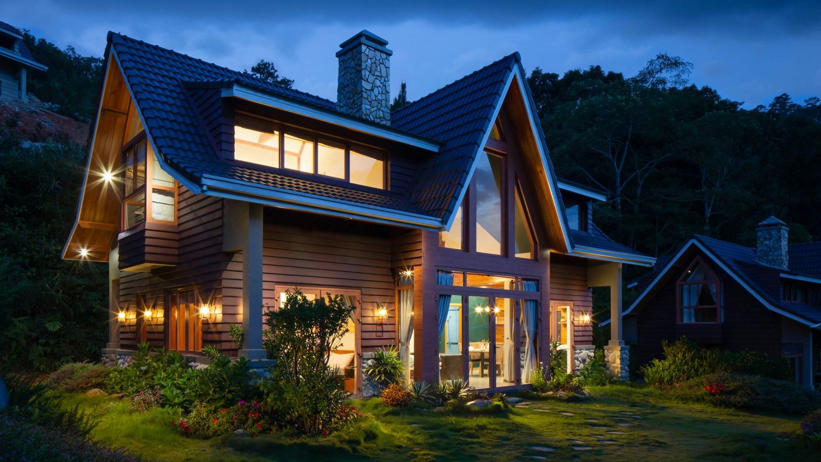 Wood-sided house with lit windows at dusk