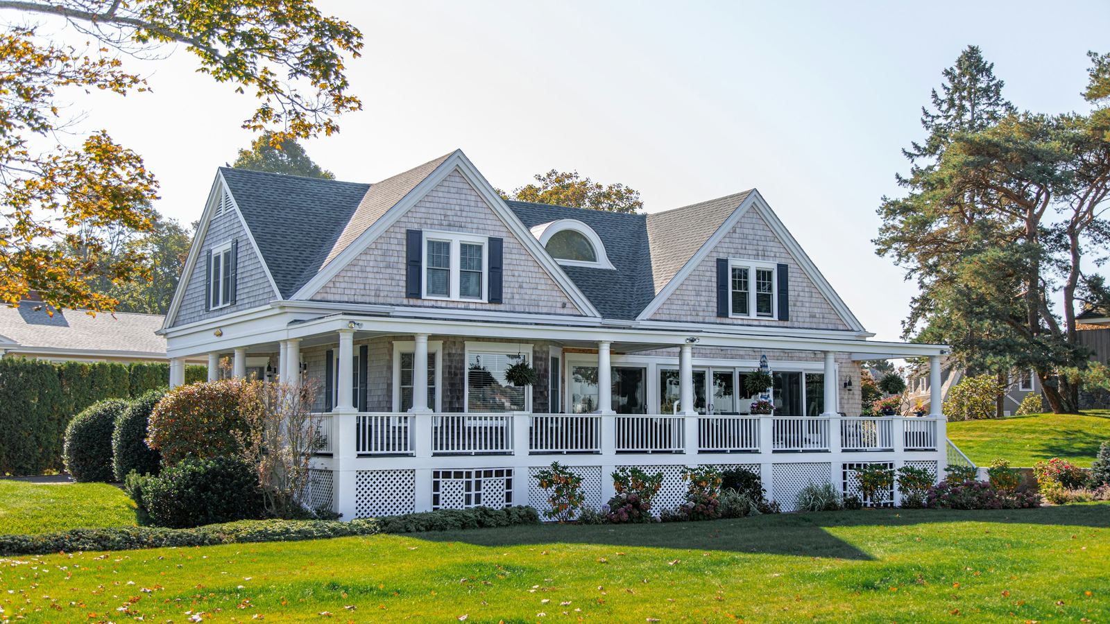 White two-story house with a wraparound porch and a green lawn